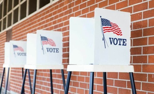 Voting booths set up in front of a brick wall.